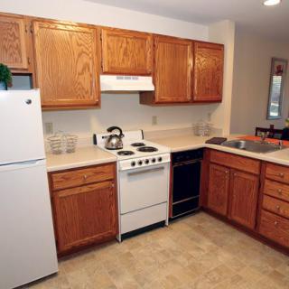 A cozy kitchen with wooden cabinets and essential appliances including a stove and refrigerator.