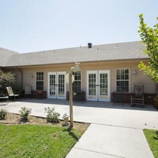 A patio area in front of a building with multiple windows and a well-maintained garden.