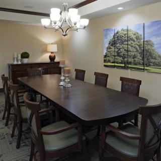 A well-furnished dining room with a long table, surrounded by chairs and lit by an elegant chandelier.