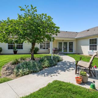 A residential backyard featuring a well-maintained lawn, a garden with shrubs, and a patio area with outdoor seating.