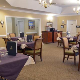 A cozy dining area with neatly arranged tables and chairs, adorned with chandeliers and soft lighting.