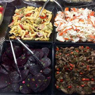A variety of salads including pasta, potato, beet, and vegetable options at a salad bar.