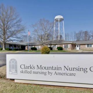 Clarks Mountain Nursing Center with a prominent sign and water tower in the background.