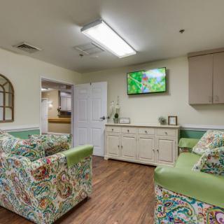 A cozy waiting room with patterned sofas and a television on the wall.