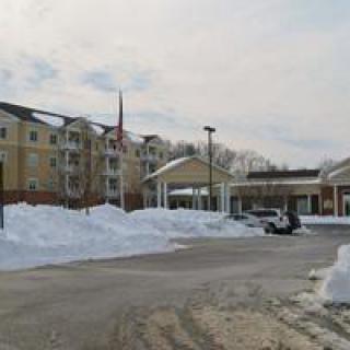 A snowy day at a hotel with a parking lot.