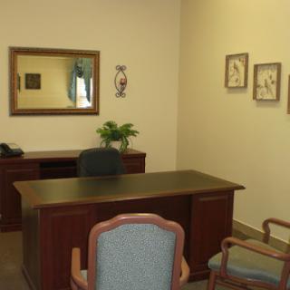 A well-organized office space featuring a wooden desk, comfortable chairs, and decorative wall art.