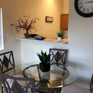 A cozy dining area with a glass table and decorative plants.