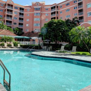 A luxury hotel with a large swimming pool surrounded by lush greenery.