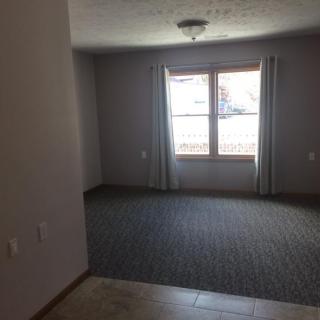 An empty room with carpet flooring and a window covered by curtains.