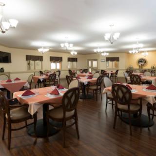 A well-lit dining room with neatly arranged tables and chairs, featuring elegant table settings.