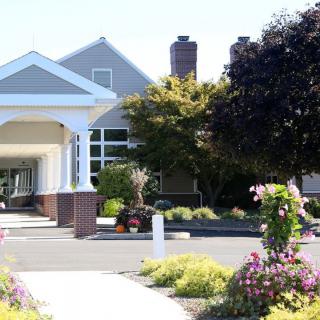 A well-maintained building entrance with landscaping, including trees and flowers.