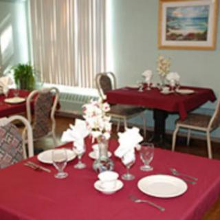 A dining area with tables set for guests, featuring red tablecloths and neatly arranged place settings.