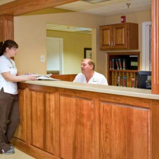 A staff member assists a visitor at the reception desk.