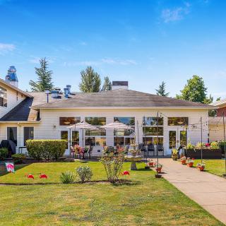 A beautiful house with a well-maintained garden and patio on a sunny day.