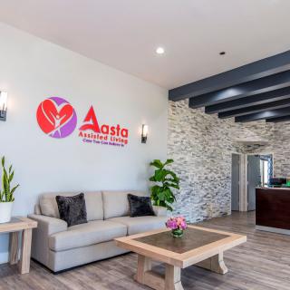 A modern reception area with a sofa, table, and decorative plants.