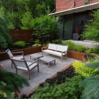 A modern garden patio with comfortable outdoor seating surrounded by lush greenery.