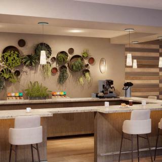 A modern coffee bar with plants displayed on the wall and stylish pendant lighting.