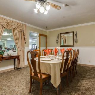 A traditional dining room with a long table set for dinner, surrounded by elegant wooden chairs and adorned with a chandelier.