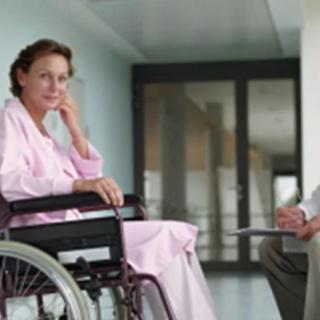 A patient in a wheelchair having a consultation with a doctor in a hospital hallway.