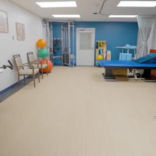 A well-lit therapy room equipped for rehabilitation with various exercise aids and comfortable seating.