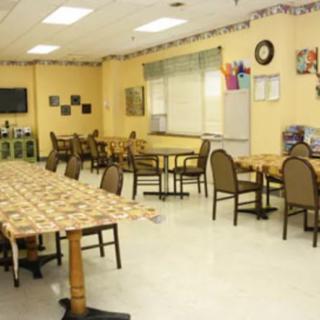 An empty dining area with tables and chairs arranged neatly, featuring simple decorations.