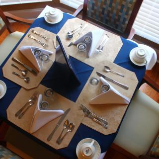 A formal dining table set for four with elegant napkin folds and complete place settings.