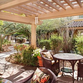 A cozy patio area with comfortable seating surrounded by lush greenery.