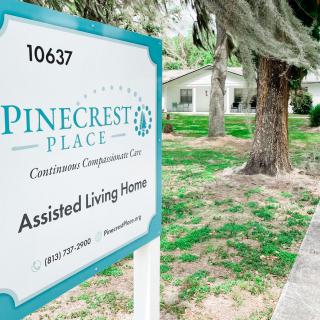 Sign for Pinecrest Place Assisted Living Home set in a landscaped area.