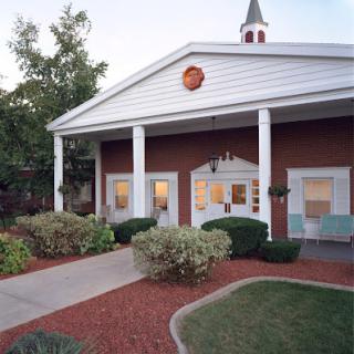 A charming building with a welcoming entrance, surrounded by well-maintained gardens.