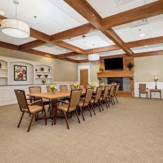 A spacious and elegantly designed meeting room featuring a long table, comfortable seating, and a cozy fireplace.