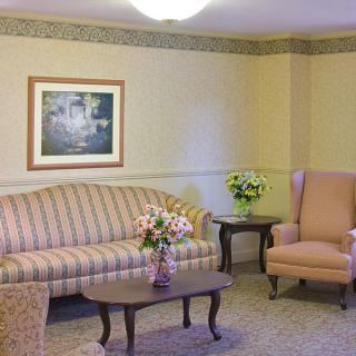 A cozy living room with a striped sofa, armchair, and coffee table adorned with flowers.