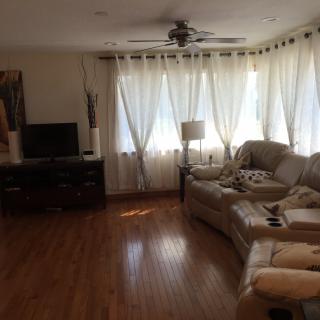A cozy living room with a sofa, TV, and natural light streaming through the curtains.