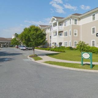 A view of a residential apartment complex with a parking lot and green spaces on a sunny day.