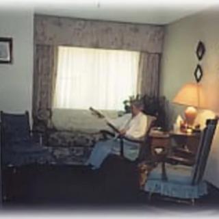 A cozy living room with a person reading near a lamp.