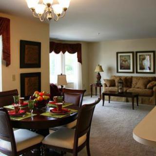 A beautifully decorated dining and living area with a dining table set, chandelier, and cozy seating.