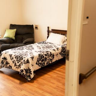 A cozy bedroom featuring a bed with patterned bedding and a comfortable recliner.