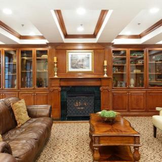 A traditional living room featuring a fireplace, wood paneling, and built-in shelves with a sofa and coffee table.