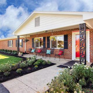 A well-maintained brick house with a landscaped front yard and outdoor seating area.