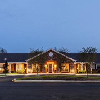 A well-lit building exterior during the evening with surrounding landscaping.