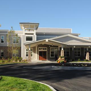 A modern residential building with a landscaped entrance on a sunny day.