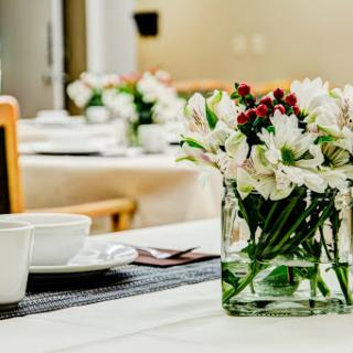 A beautifully arranged table featuring a floral centerpiece and coffee cups, perfect for a cozy dining experience.