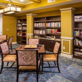 A cozy library reading area with bookshelves, chairs, and a table.
