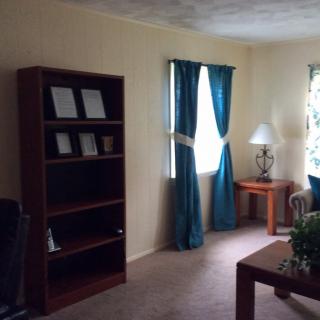 A cozy living room with a bookshelf, blue curtains, and a side table near the window.