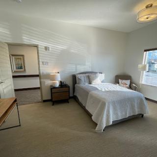 A bright and minimalistic bedroom featuring a single bed, nightstand, and natural lighting.