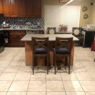 A modern kitchen with a central island and two stools on a tile floor.