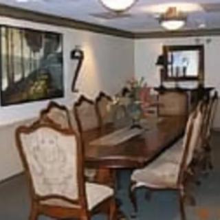 A formal dining room with a long wooden table and upholstered chairs, adorned with wall art and soft lighting.