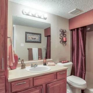 A cozy bathroom with wooden cabinets, a mirror, and a shower area.