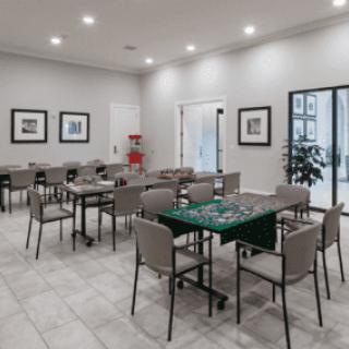 A modern meeting room with several tables and chairs arranged neatly under bright lighting.