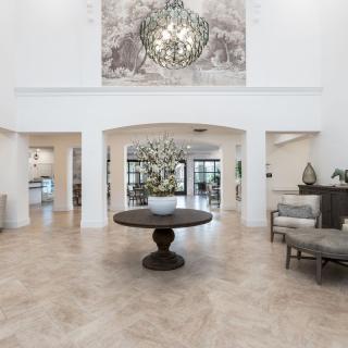 A spacious lobby with a central table, decorative artwork, and a chandelier.