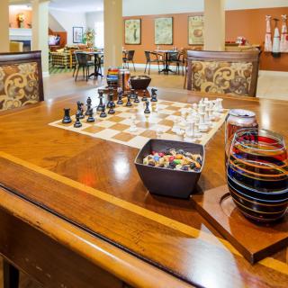 A cozy game room with a chessboard set up on a wooden table, surrounded by comfortable seating.
